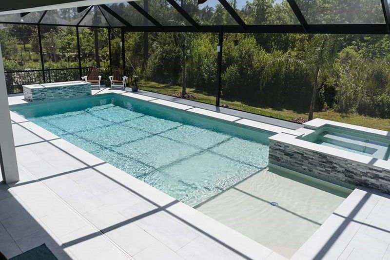 Modern backyard pool with turquoise water, hot tub, and covered patio in bright sun