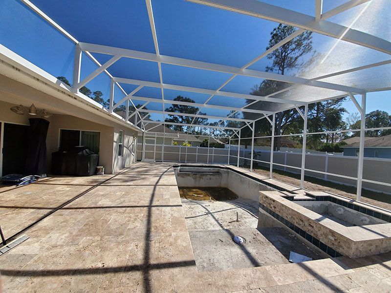 Backyard pool area under construction with white frame canopy and concrete patio surrounding empty pool.