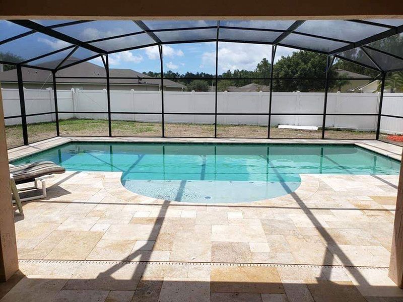 Screened-in backyard pool with clear blue water and a tan tile patio