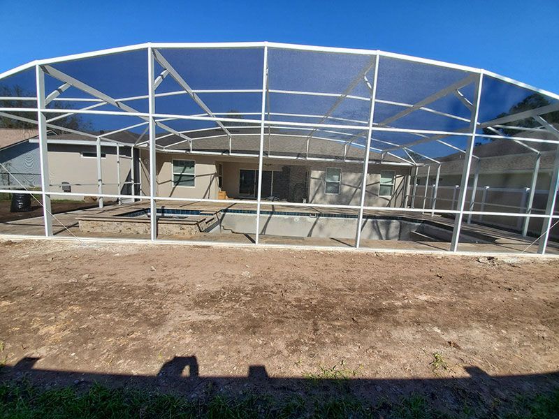 Empty metal-frame structure with a blue canopy covering a concrete area outdoors