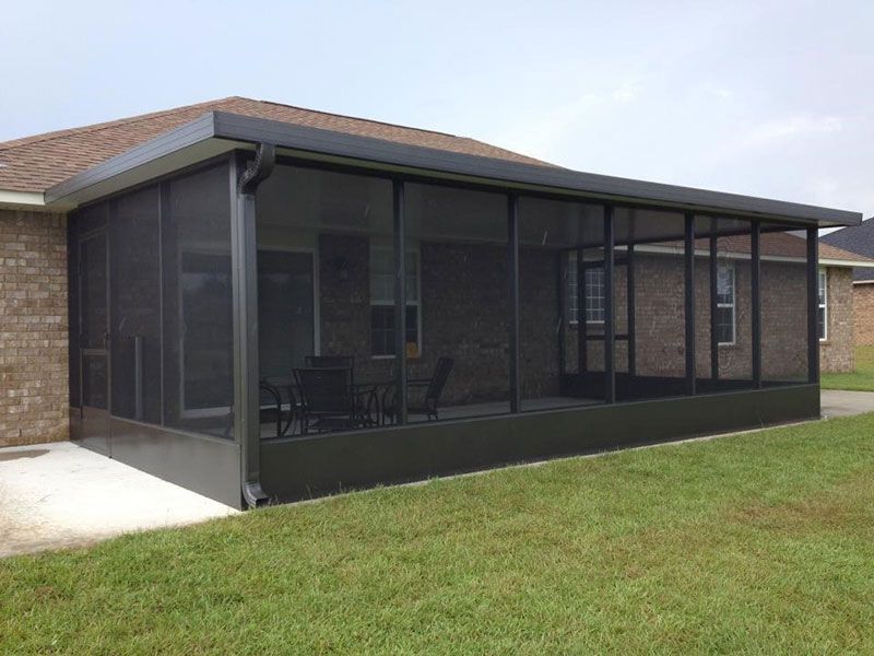 Screened back porch on a brick house with dark mesh panels and a grassy yard.