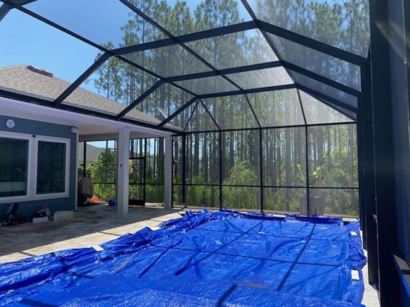 Backyard pool under construction, covered with a blue tarp inside a black metal frame canopy