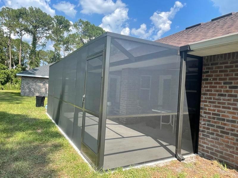 Mesh screened porch attached to a brick house on a sunny day