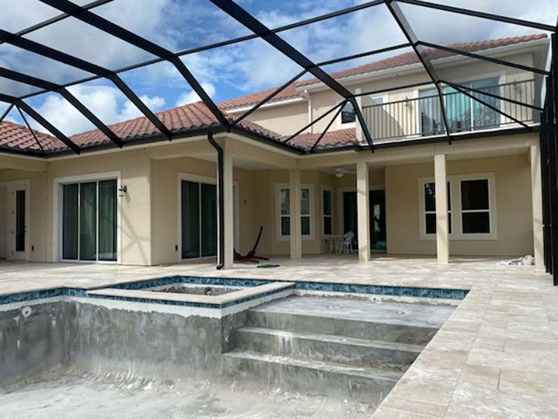 Patio with a swimming pool, tiled deck, and a black-framed screened roof extension beside a house