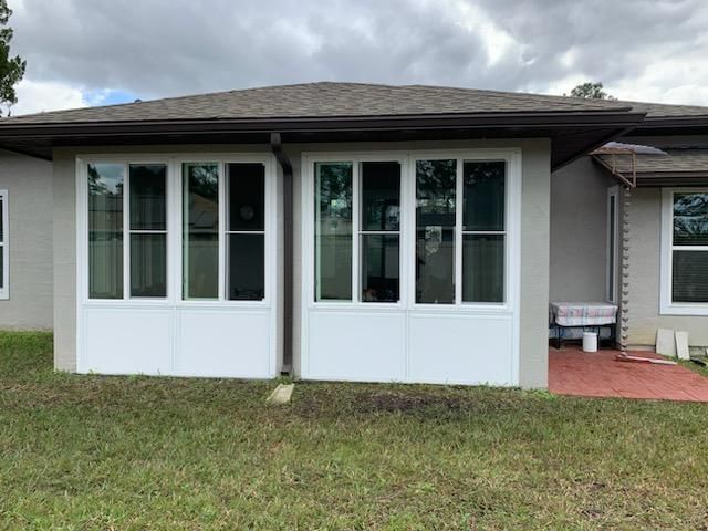 Front view of a house with white double doors and windows on a small grassy lawn