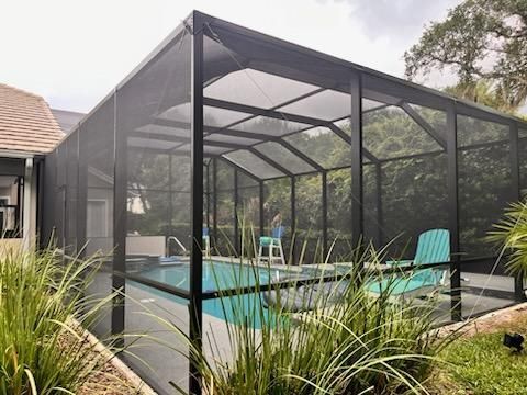 Screened backyard pool enclosure with lounge chairs and turquoise water