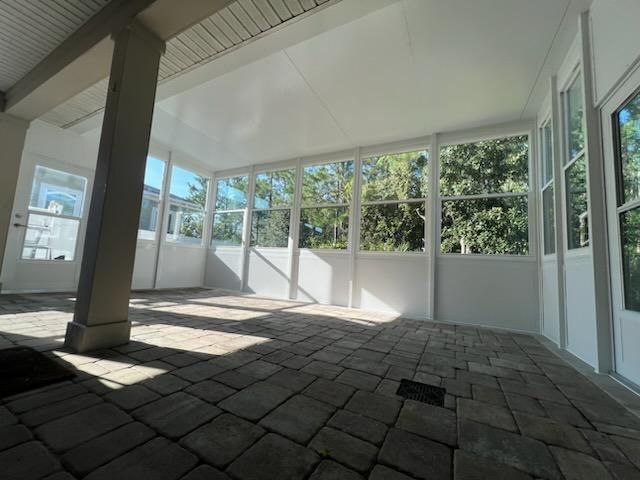 Bright sunroom with large windows, tiled floor, and views of trees outside