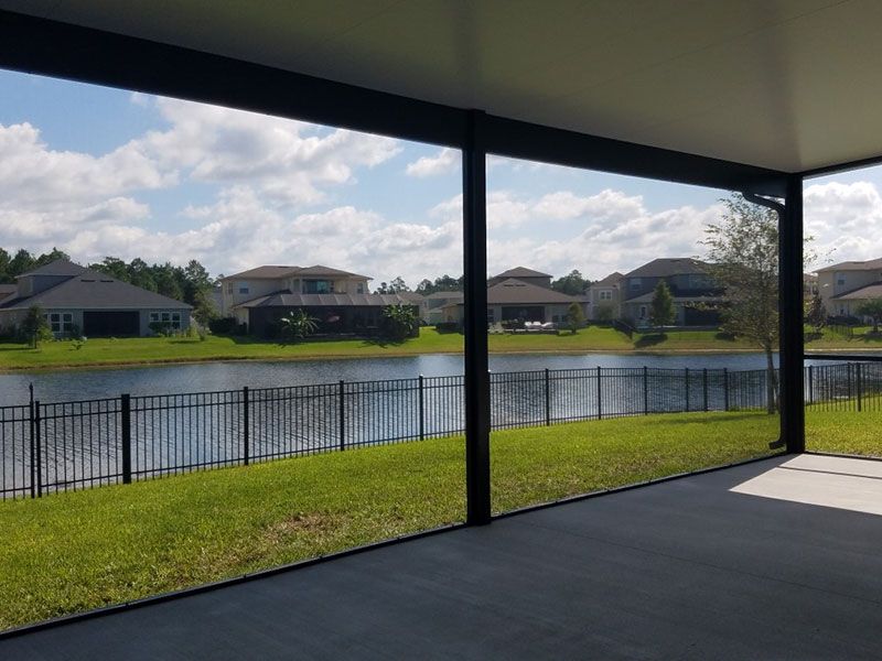 Covered patio overlooking a pond, grassy yard, and houses across the water