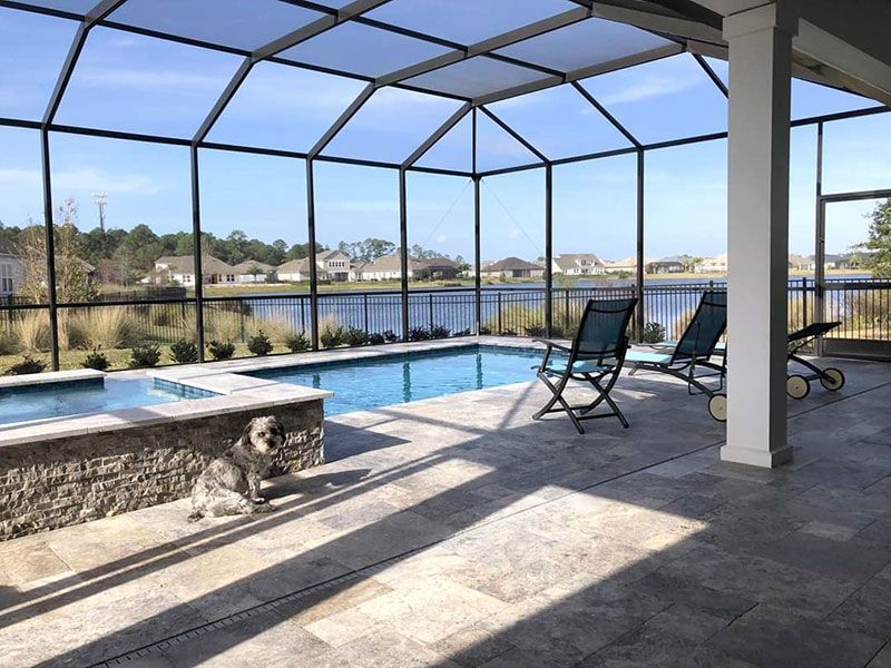 Screened-in pool patio with lounge chairs and a lake view under blue sky