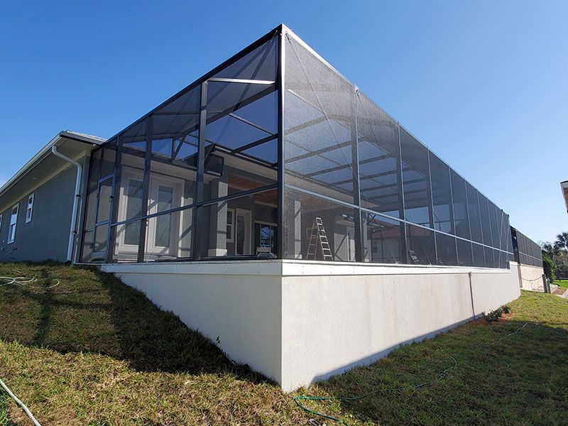 Modern glass-enclosed building with a slanted roof on a white base, set on a grassy slope under blue sky