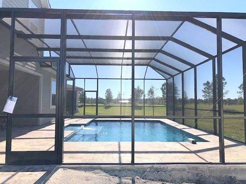 Screened-in backyard pool with blue water, patio, and sunny lawn beyond