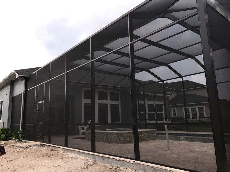 Screened patio enclosure beside a modern house, with black metal framing and mesh panels