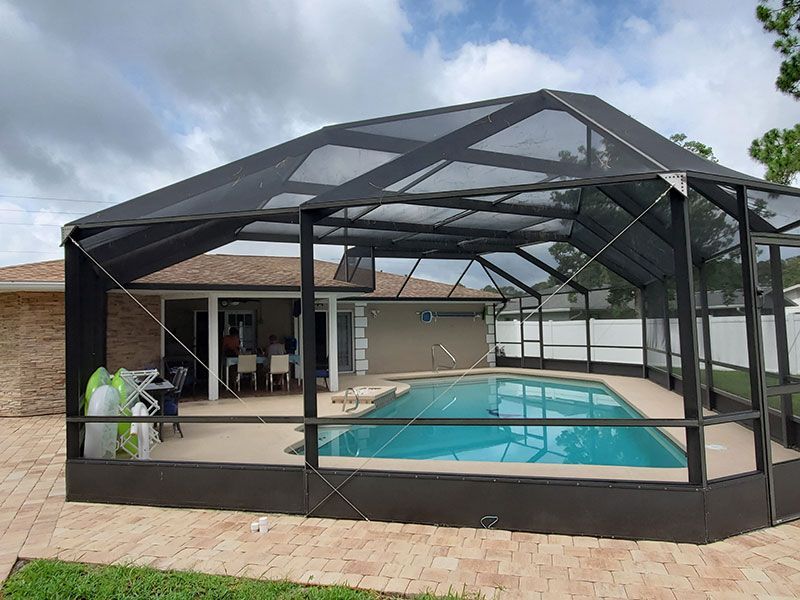 Screened backyard pool enclosure with a covered patio and cloudy sky above