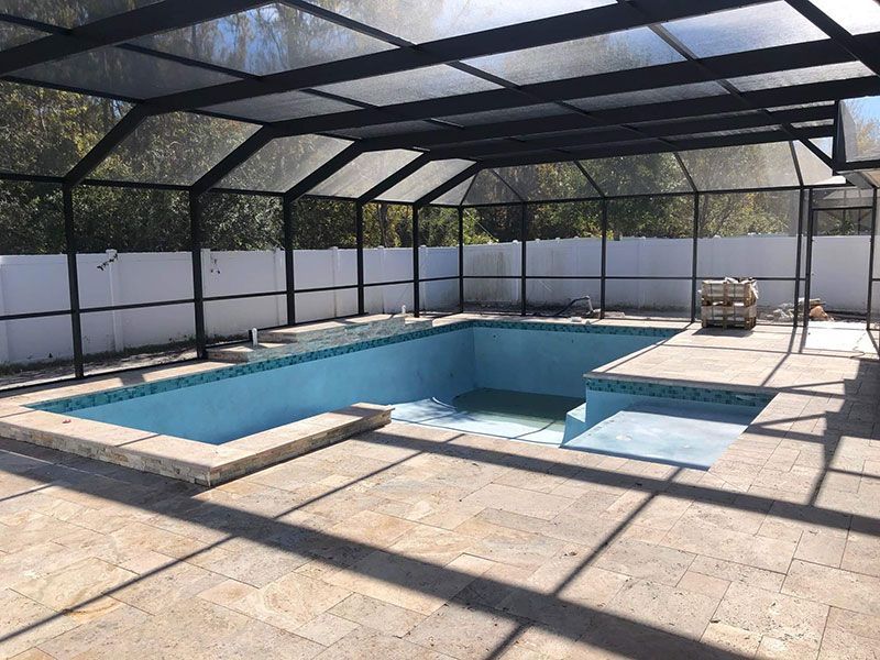 Screened-in backyard patio with a rectangular pool and hot tub under a black metal enclosure