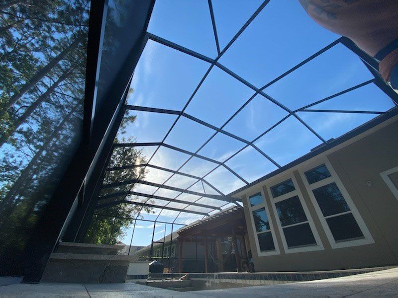 Screened courtyard beside a house, with blue sky visible overhead.
