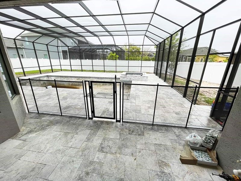 Empty screened patio with stone flooring and metal-framed doors, viewed from inside the enclosure