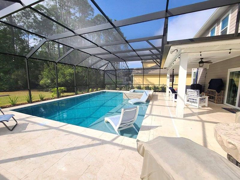 Screened-in patio with a turquoise pool and lounge chairs beside a house