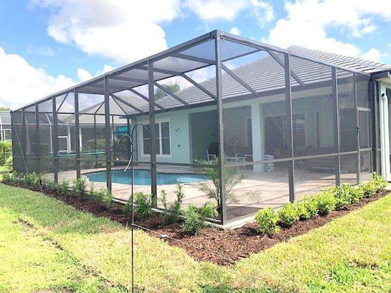 Screened backyard patio and pool area beside a modern house on a sunny day