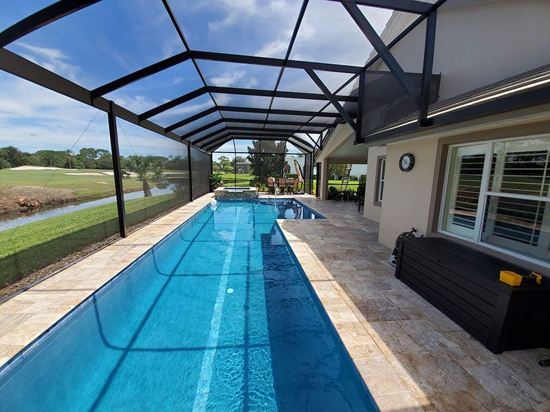 Screened backyard pool with blue water beside a patio and house exterior