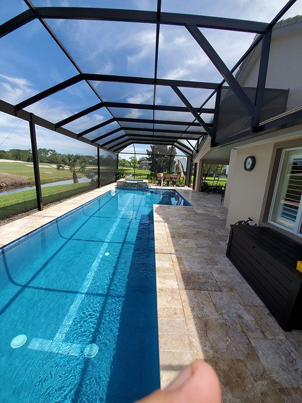 Covered backyard pool with blue water, stone deck, and screened lanai overlooking a lawn.