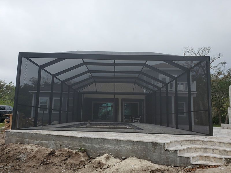 Modern screened patio enclosure with black framing on a concrete foundation, viewed front-on