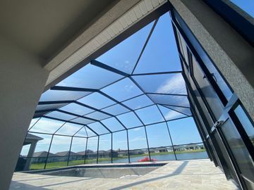 Covered outdoor pool enclosure with a clear screen roof and open view of the sky outside