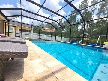 Screened-in backyard pool with blue water and lounge chairs on a sunny patio