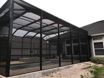 Screened-in black patio enclosure attached to a house, with a small stone courtyard.