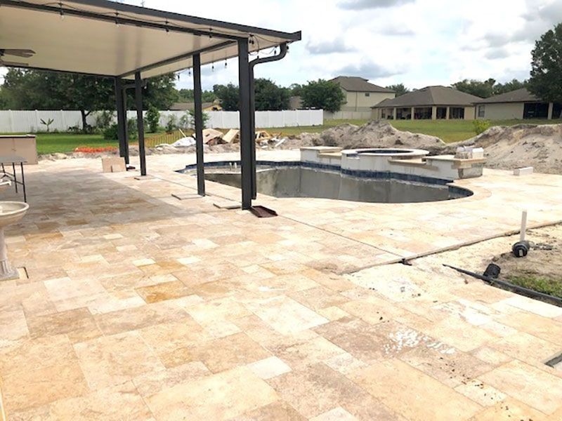 Patio with covered seating area and unfinished pool in a new backyard under construction