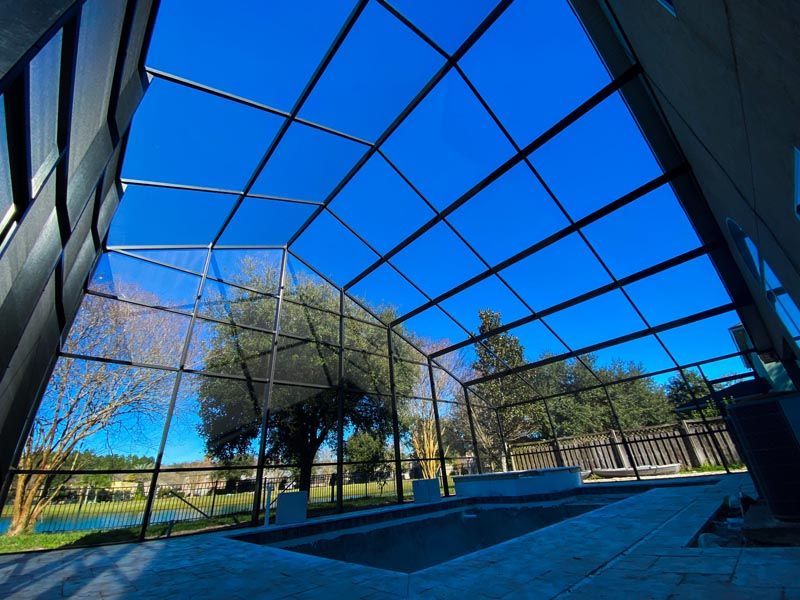 Modern glass-roofed courtyard with trees and blue sky reflected in the structure