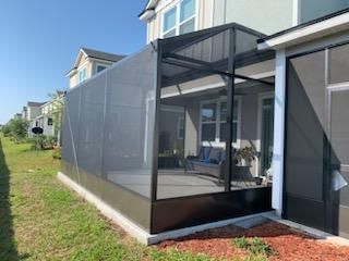 Screened patio enclosure with dark frame attached to a house