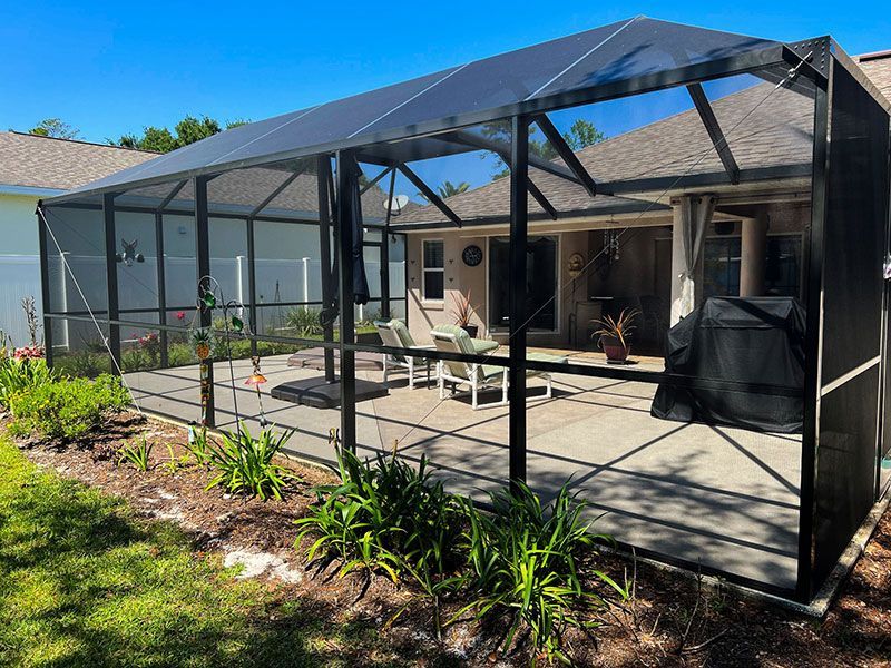 Screened patio beside a house with outdoor seating, potted plants, and a mountain view