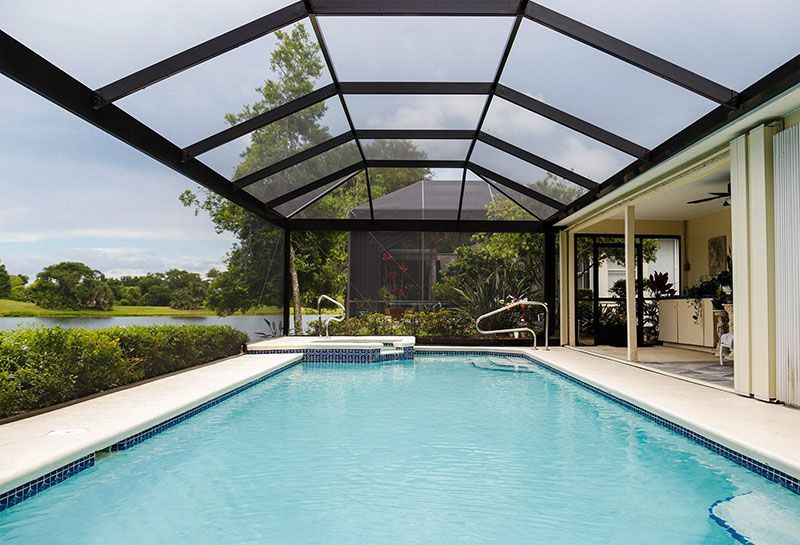 Screened-in backyard pool with turquoise water and patio beside a house