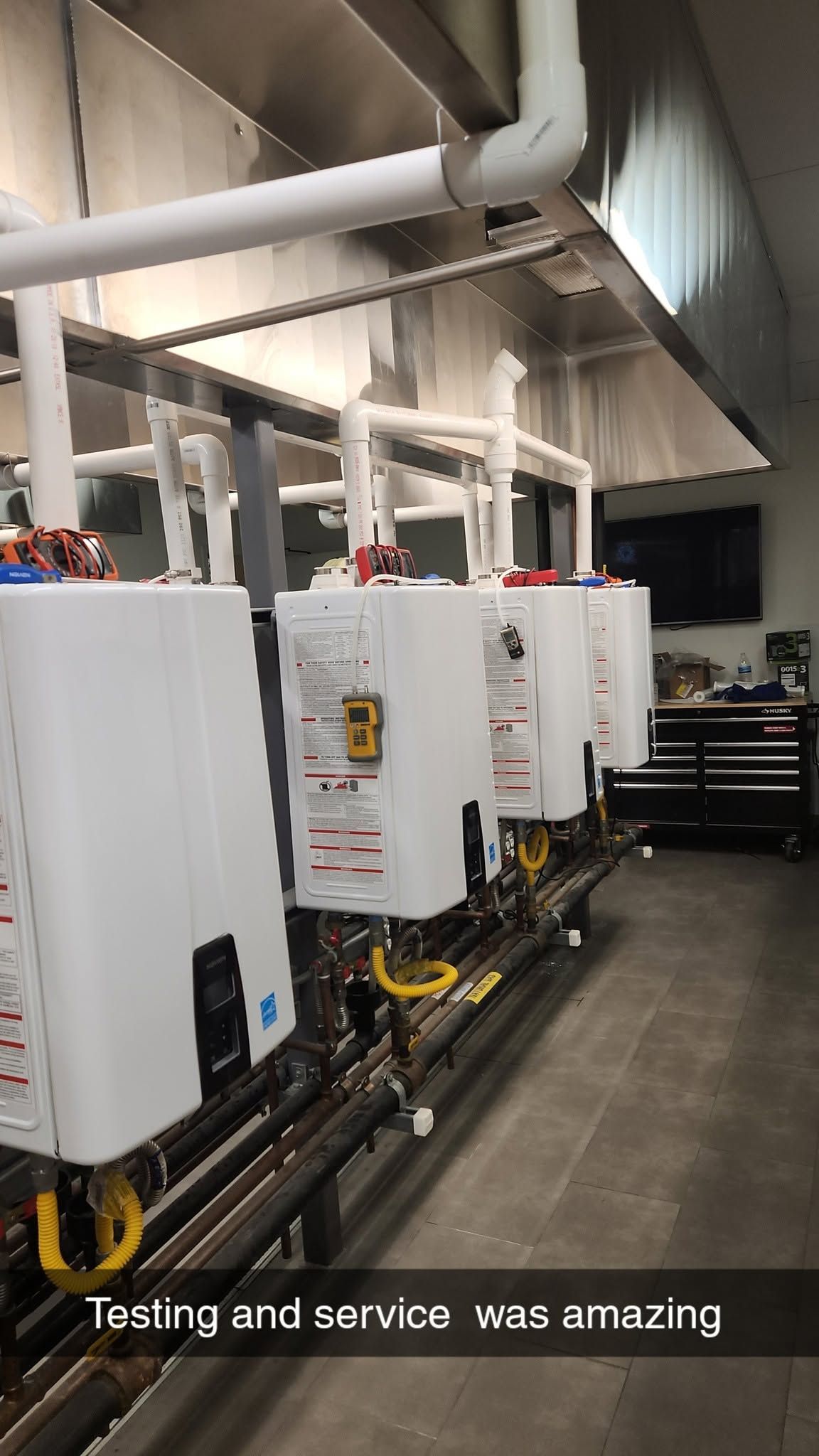 Row of white industrial control panels in a utility room with exposed pipes and cables