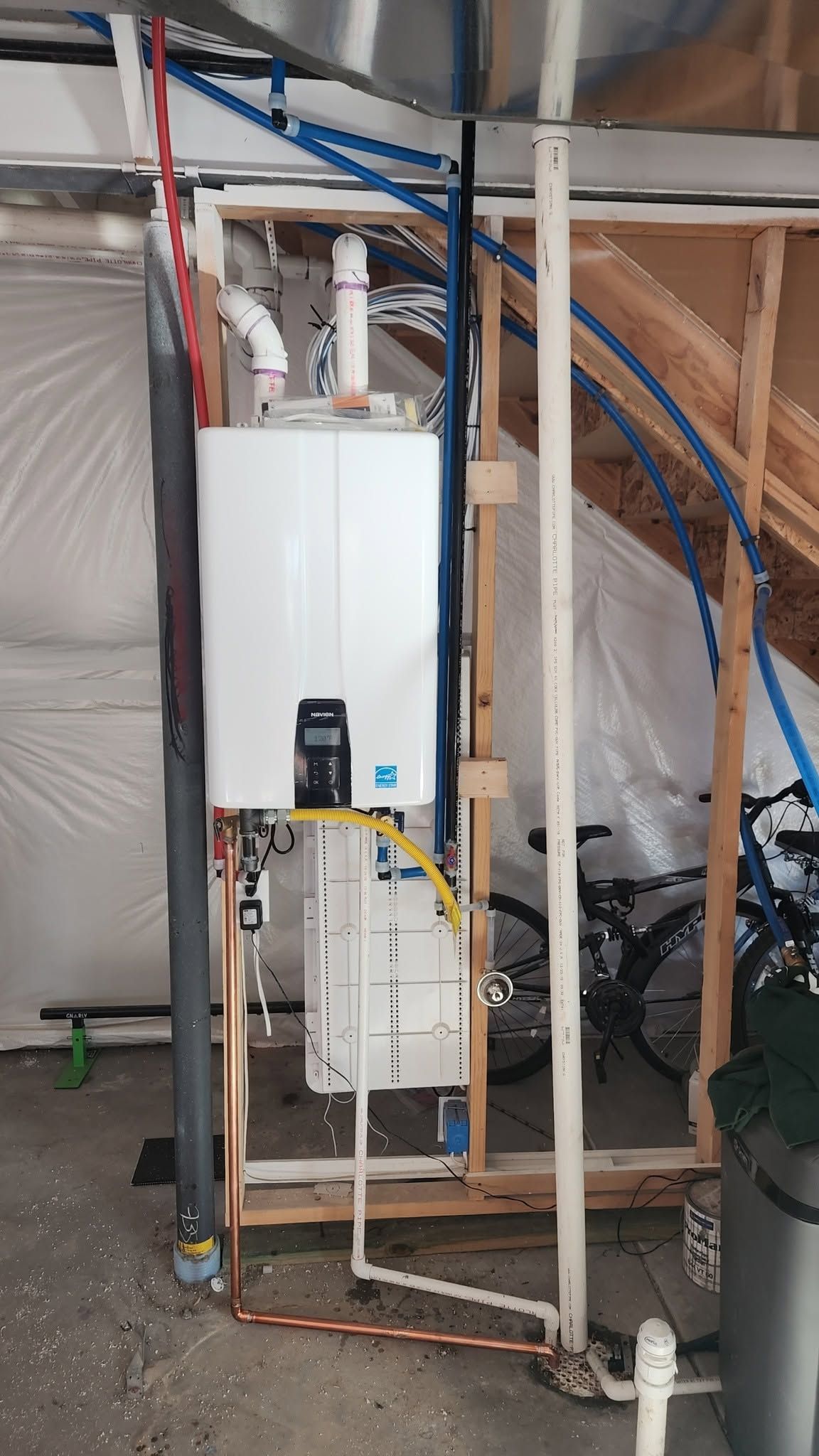 White water heater and exposed pipes in an unfinished basement utility area