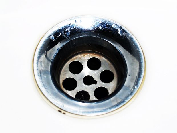 Close-up of a shiny metal sink drain with a circular grate.