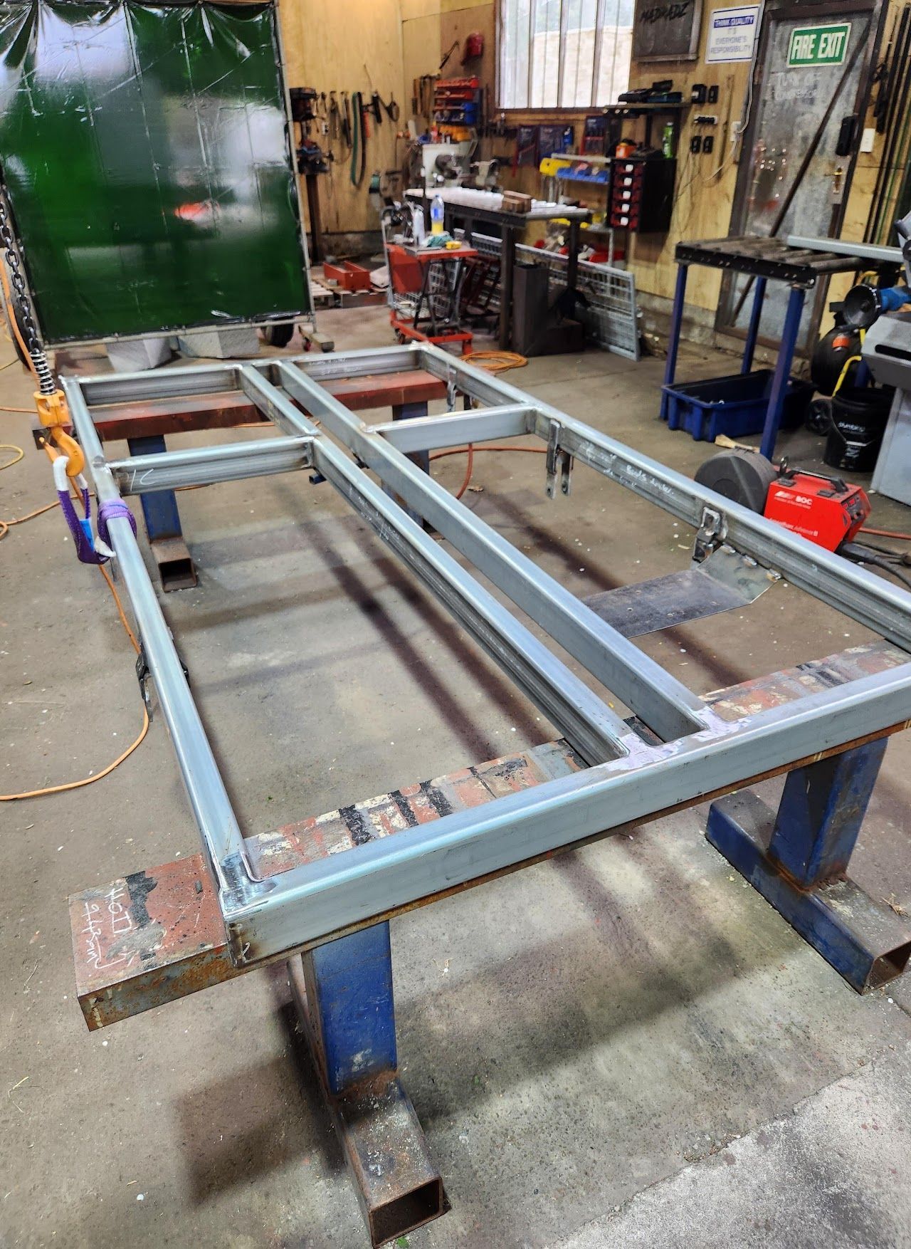 A metal frame is sitting on top of a wooden table in a workshop.