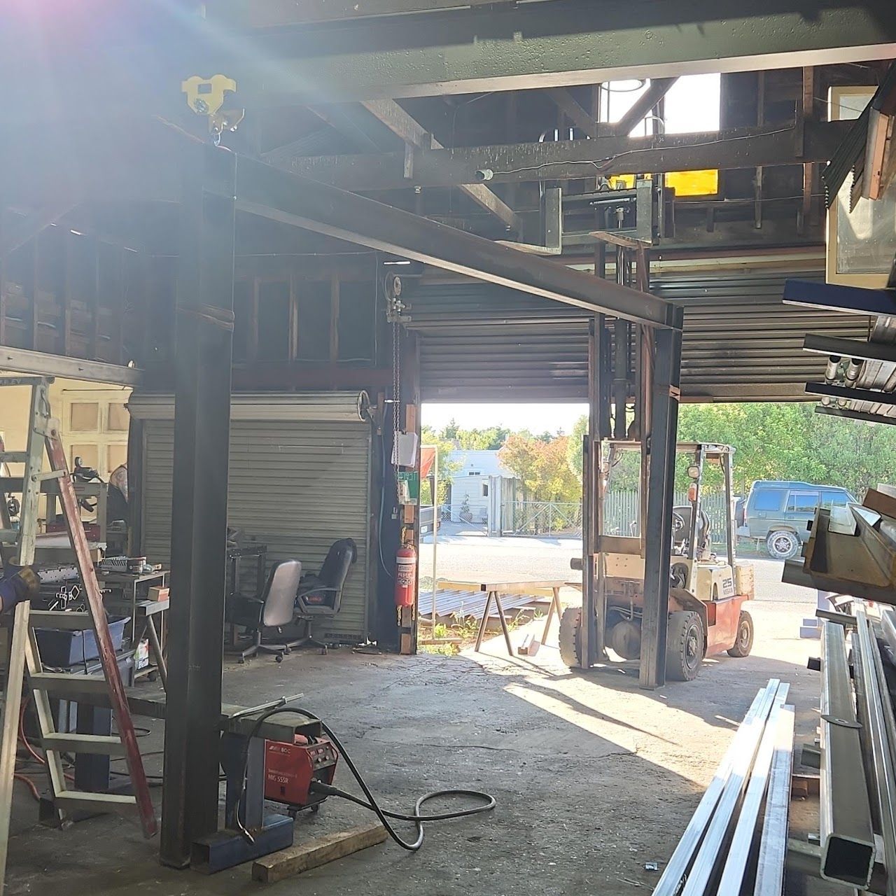The inside of a garage with a forklift and a ladder.
