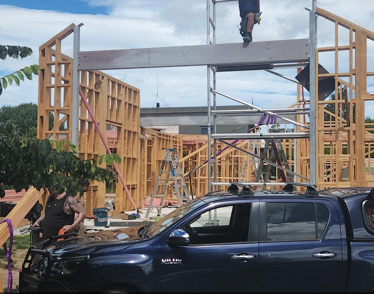 A blue truck is parked in front of a building under construction.