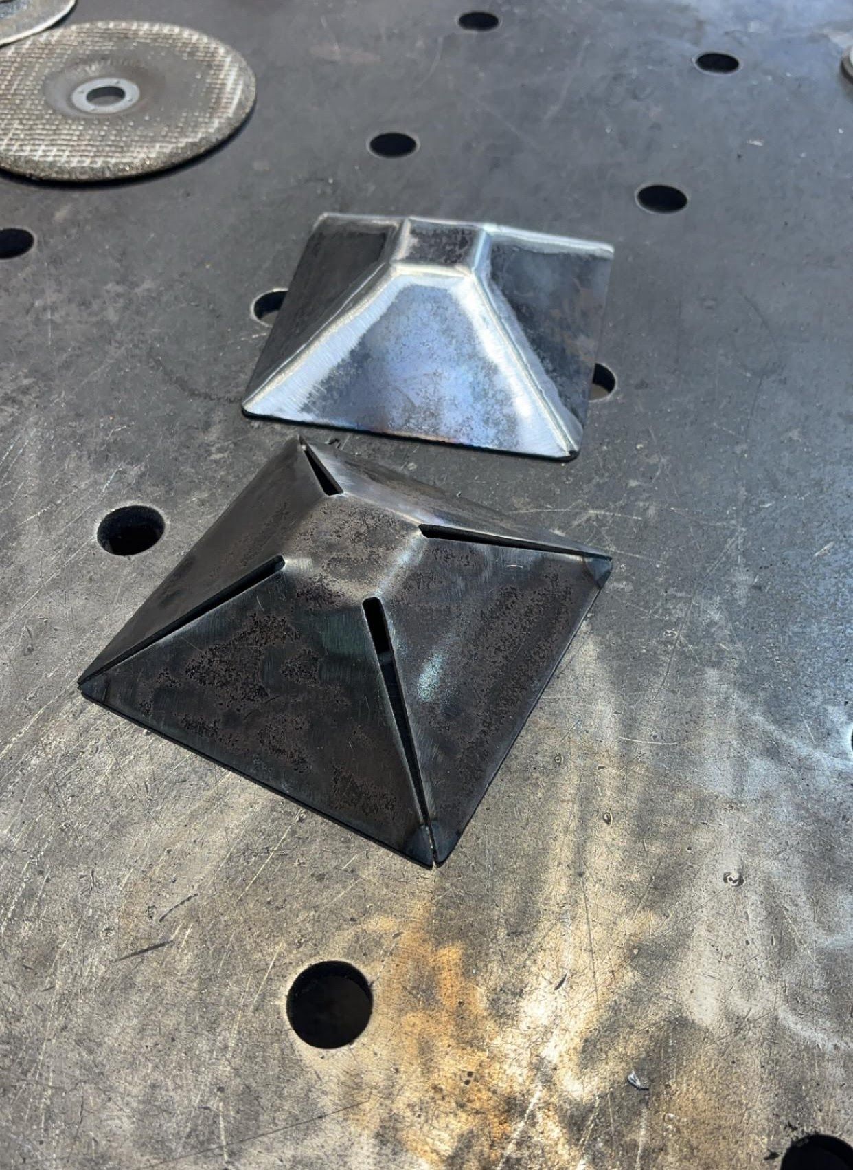 Two metal pyramids are sitting on top of a metal table.