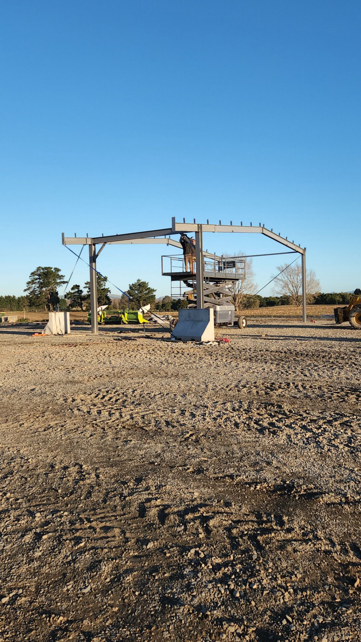 A blue truck is parked in front of a building under construction.