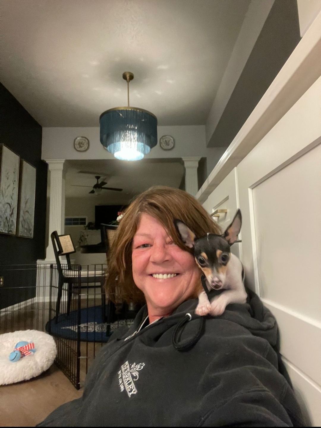 A woman is holding a small dog on her shoulder