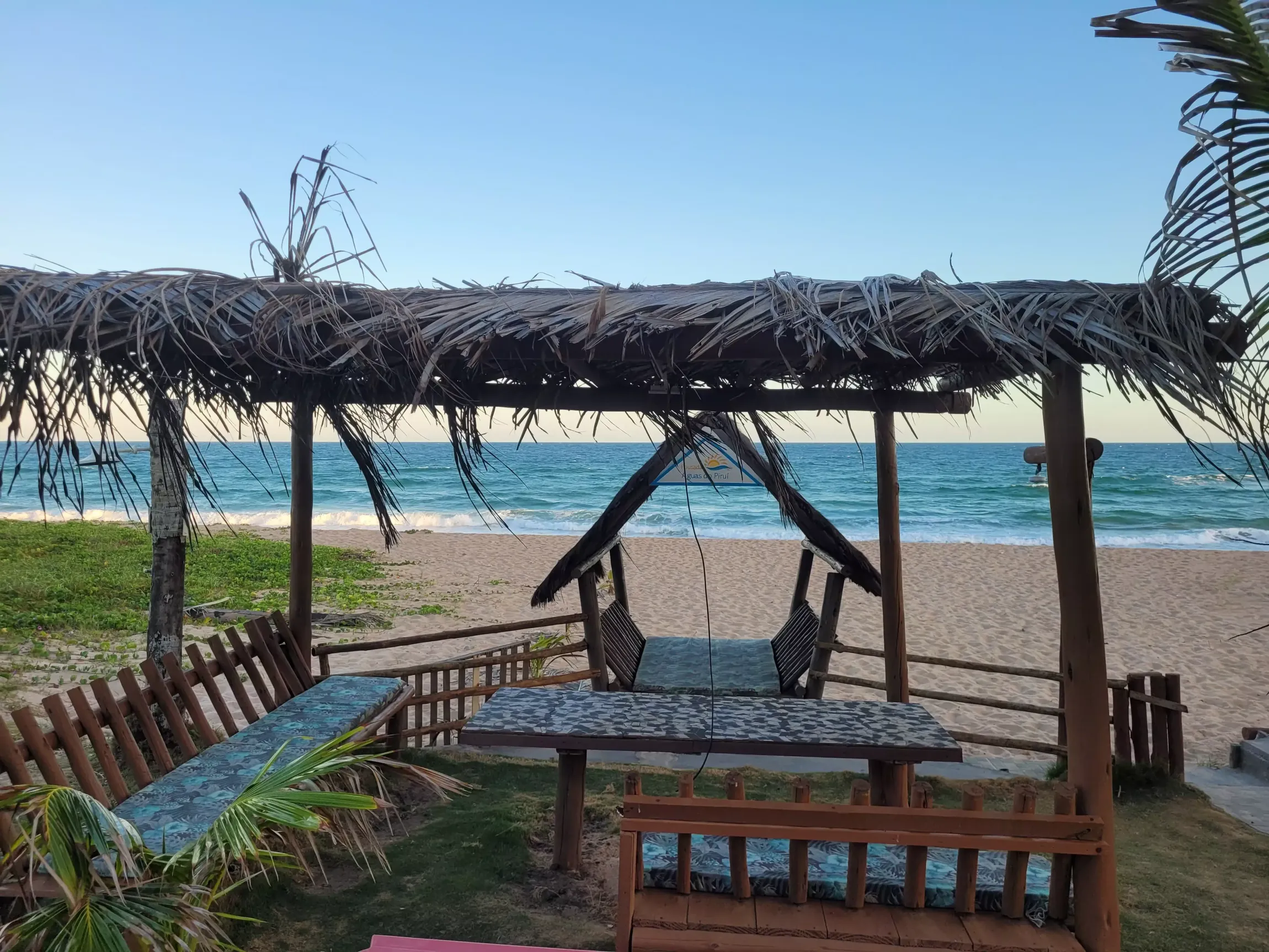 Um mirante na praia com uma mesa e cadeiras sob um telhado de palha.-Pousada Águas de Piruí