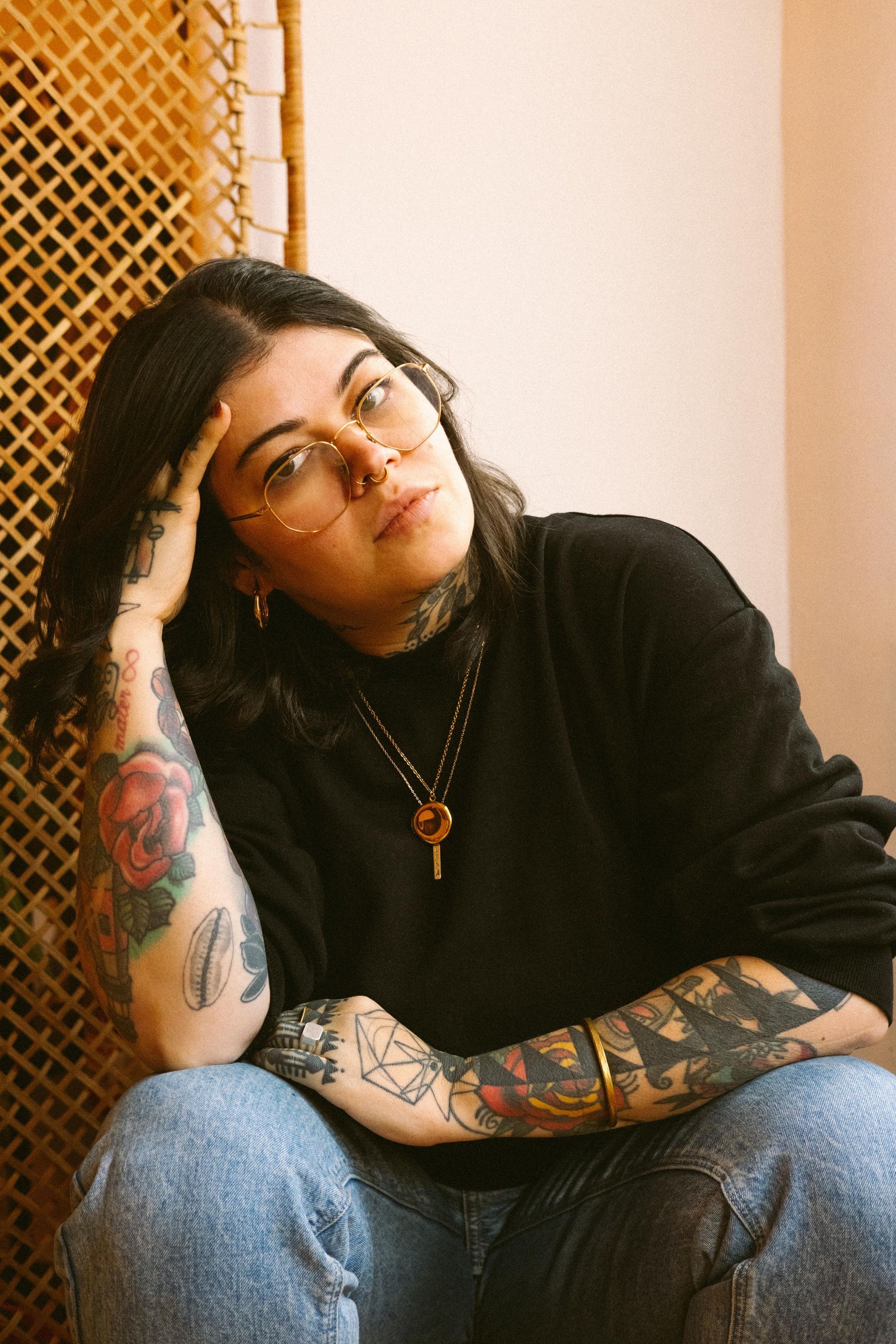 Uma mulher usando óculos e uma camisa preta tem uma tatuagem no peito.