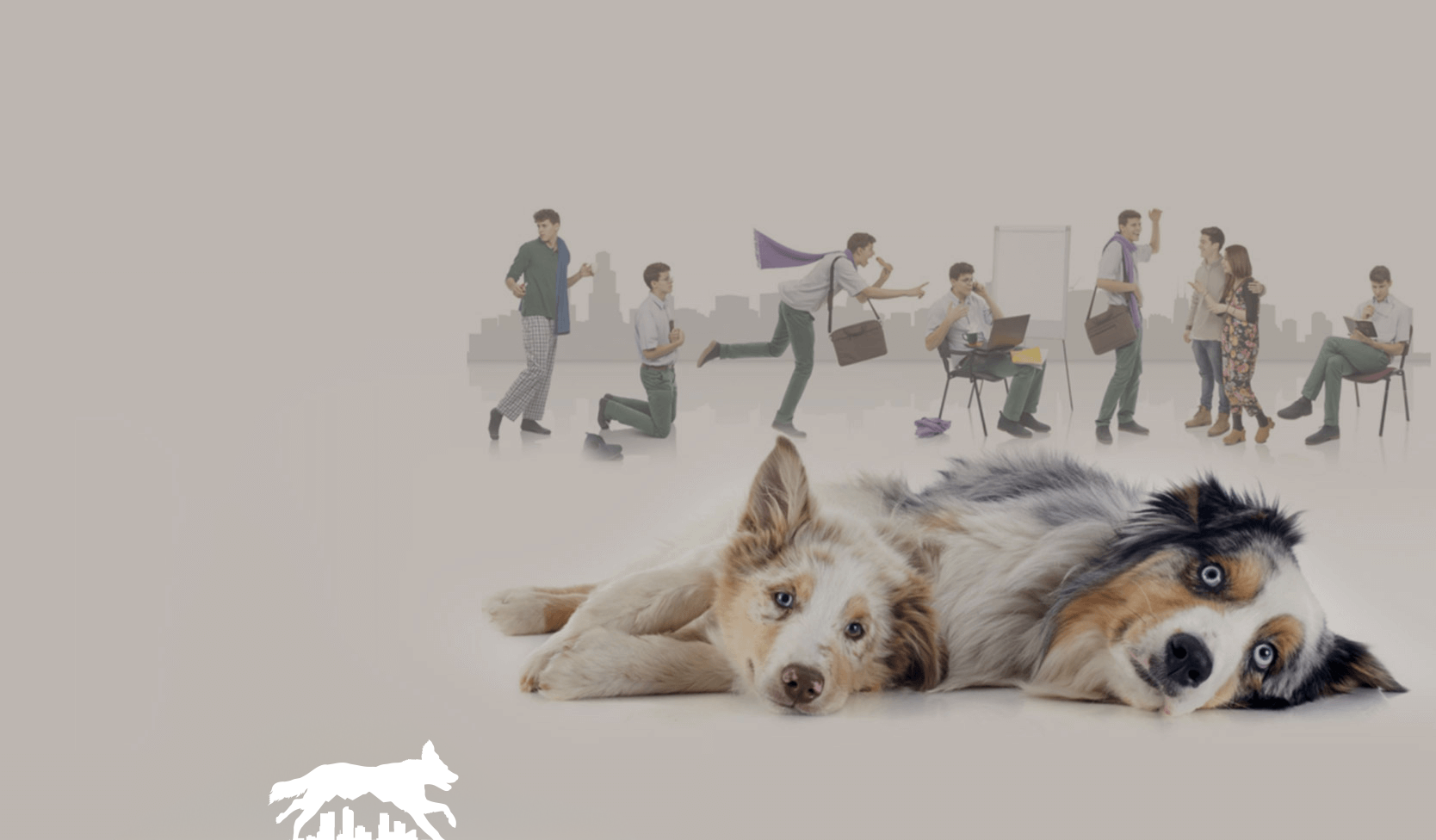 Two dogs lie in front of a blurred group of people with a dog in a modern indoor setting
