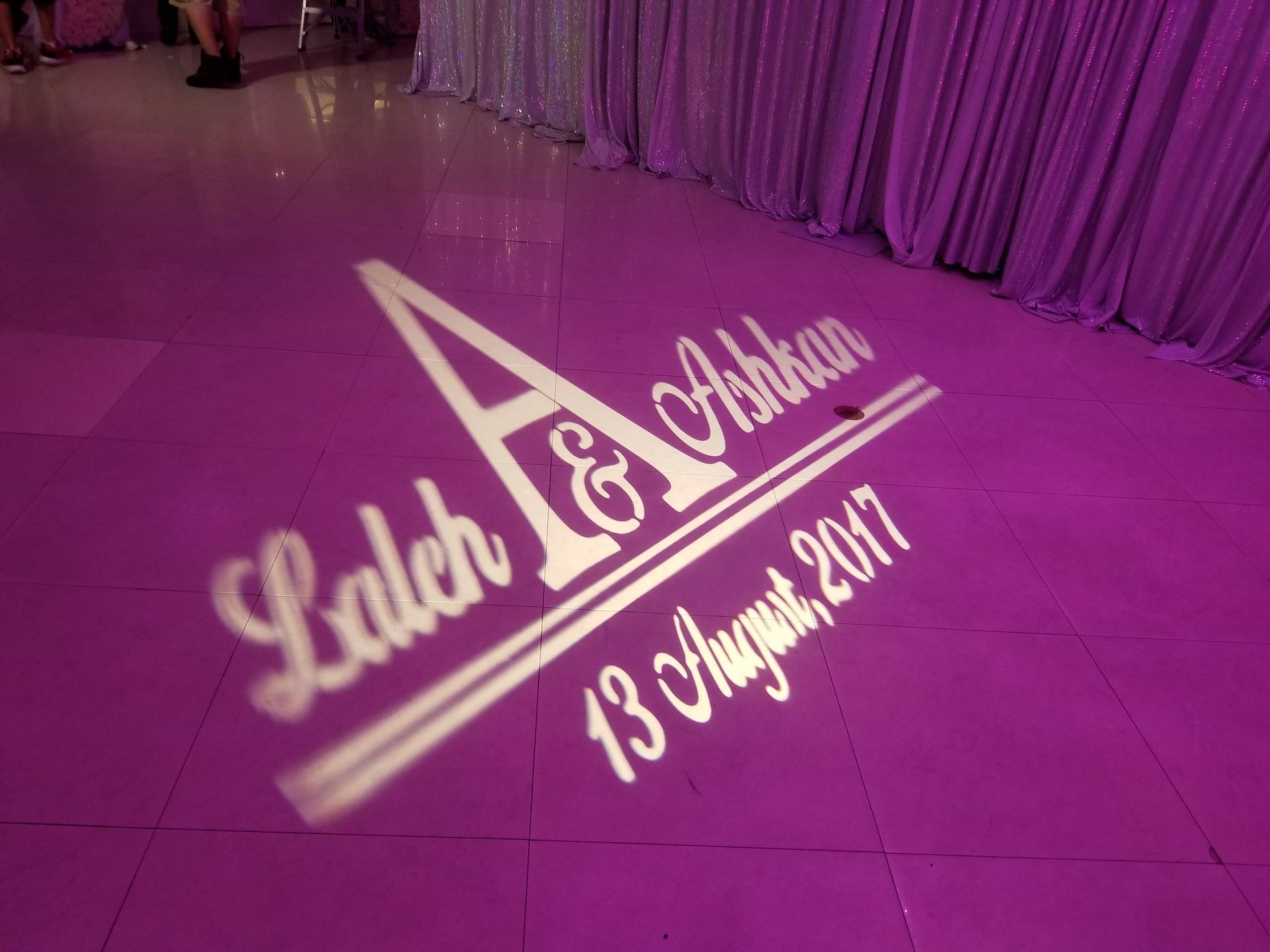 White light projection on a pink floor, displaying the names 