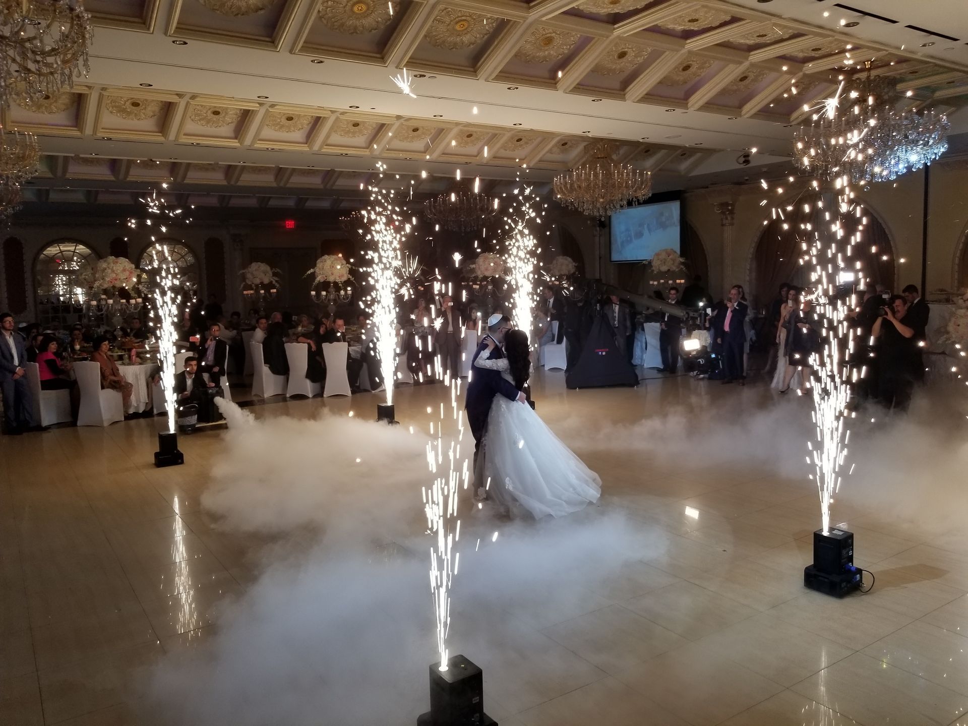 Wedding DJ Long Island NY, Bride and groom dancing at wedding; sparks and fog in a ballroom with guests and decorations.