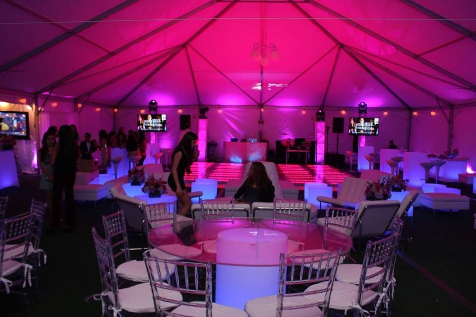 Party tent interior with pink and blue lighting, lounge seating around a central illuminated dance floor.