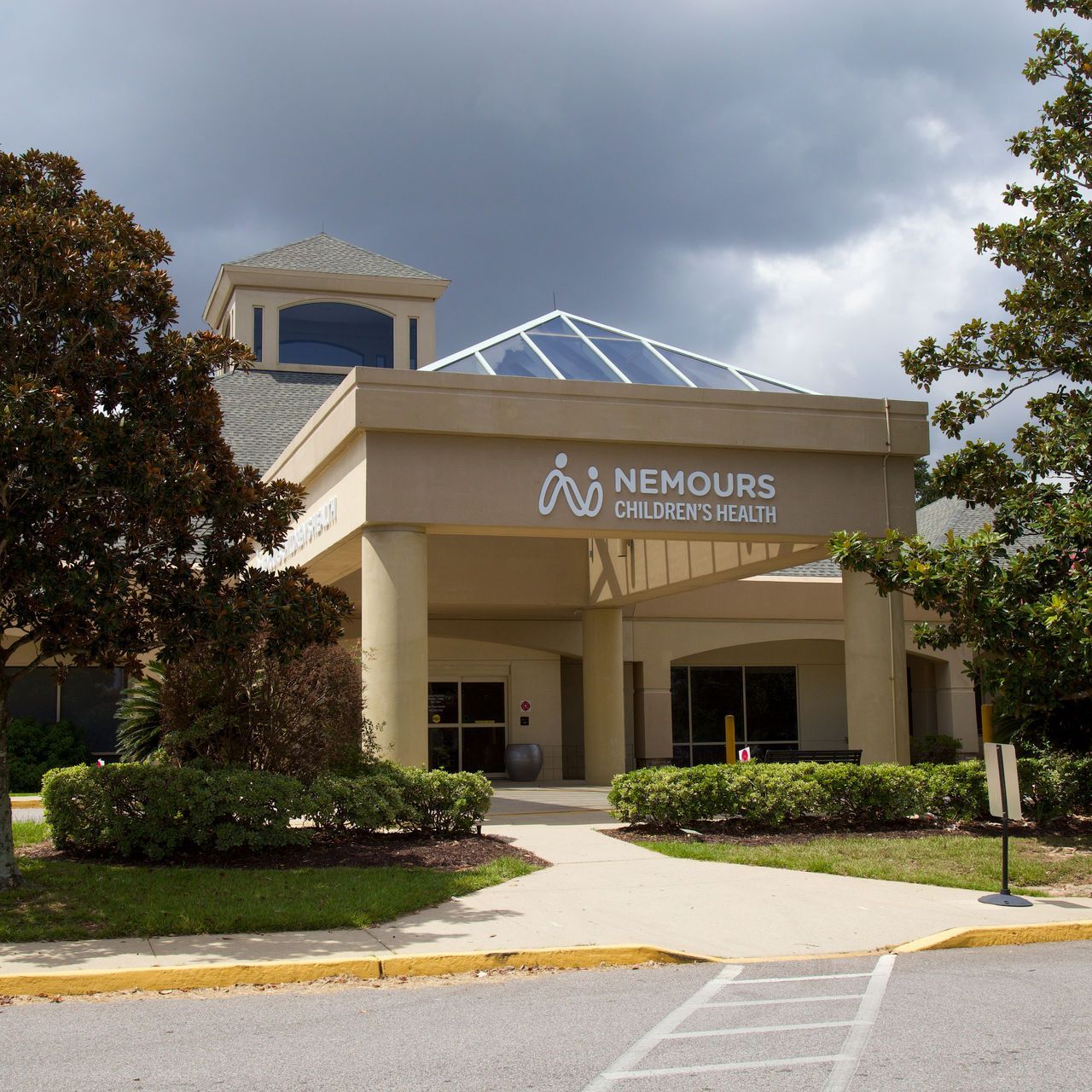 The Nemours Children's Health building exterior, featuring a glass skylight, beige columns, and manicured landscaping.
