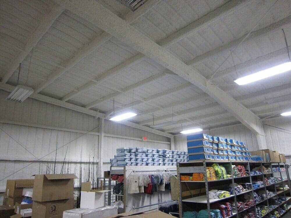A storage warehouse featuring rows of shelves stocked with clothing and items under high white ceilings and bright lights.